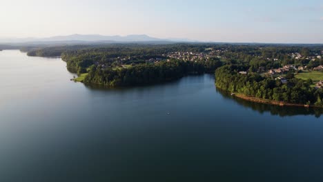 Drone-Volando-Sobre-El-Lago-Al-Atardecer-Con-Montañas-En-La-Distancia