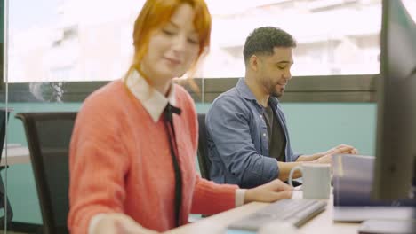 coworkers smiling while working together with computers