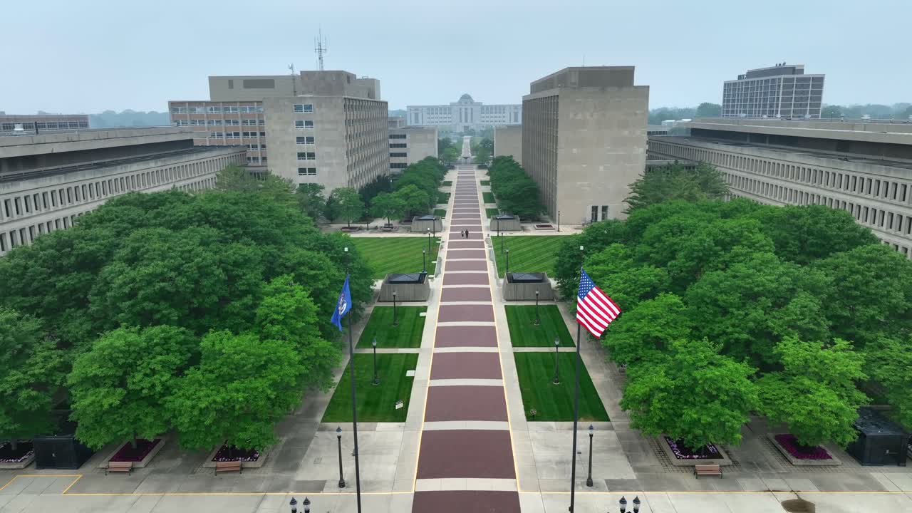 Amerikansk flag og Michigans statsflag vajende i et regeringskompleks med mange kontorer til statsansatte.
