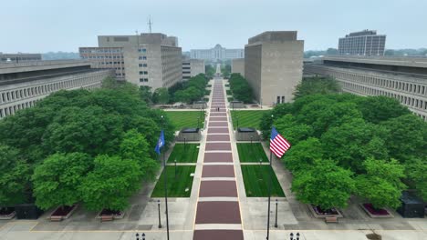 american flag and michigan state flag waving in government complex with many offices for government employees