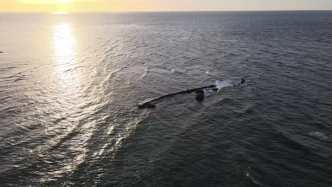 drone aerial during sunset over an ocean with a shipwreck