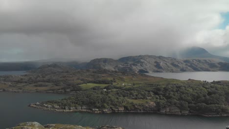 Aerial-drone-shot-of-beautiful-scottish-landscape-in-north-highlands-with-lake-bay-and-green-mountains-in-cloudy-day-uk