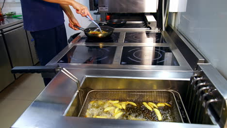 deep fryer in the kitchen restaurant. chef is cooking food in the frying pan. crispy potatoes frying in hot boiled oil. delicious meals.