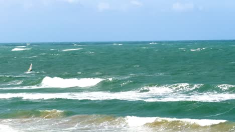 a windsurfer skillfully maneuvers through ocean waves under bright daylight at torquay beach, victoria, australia