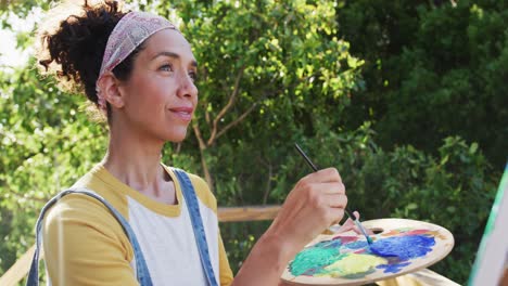 mixed race woman painting on canvas in the balcony at home