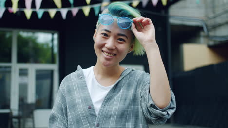 portrait of a smiling young woman with colorful hair and sunglasses