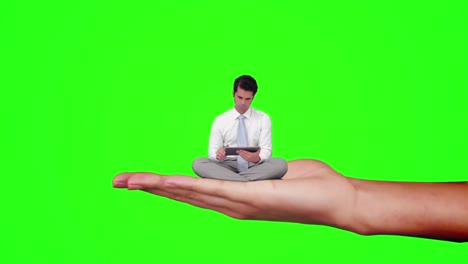 Hand-holding-sitting-businessman-focused-on-tablet-computer-against-green-screen-