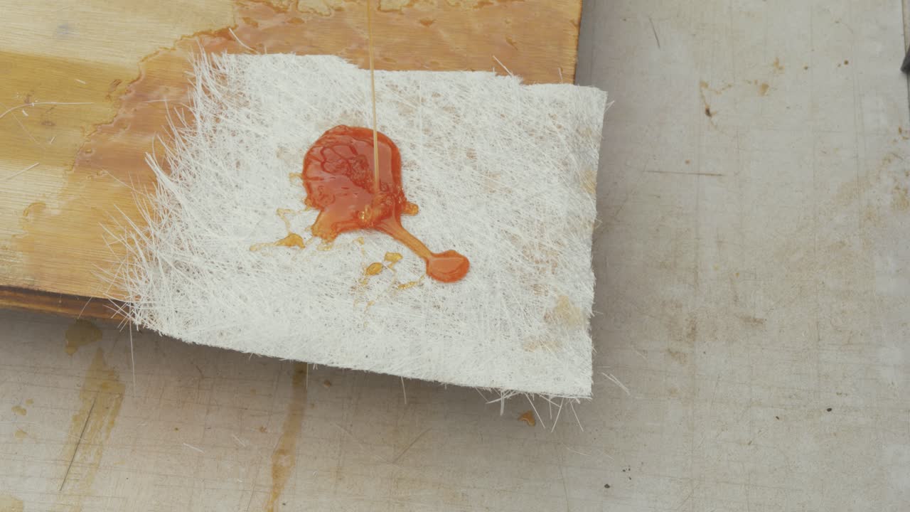 Pouring Polyester resin over chopped strand mat fiberglass