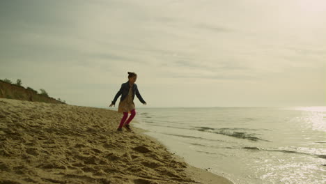 Cute-kid-running-sea-shore-in-morning.-Playful-girl-walking-away-beach-waves.