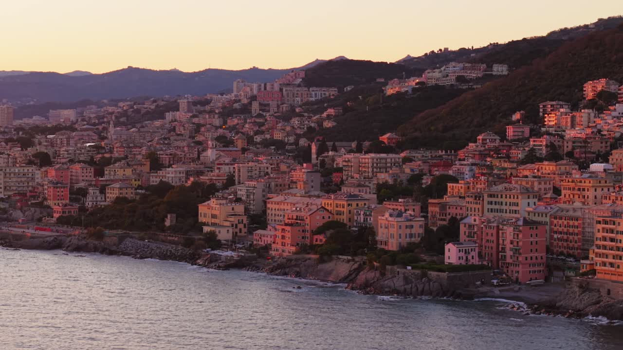 Colorful buildings along the coastline of genoa, italy, at sunset, aerial view