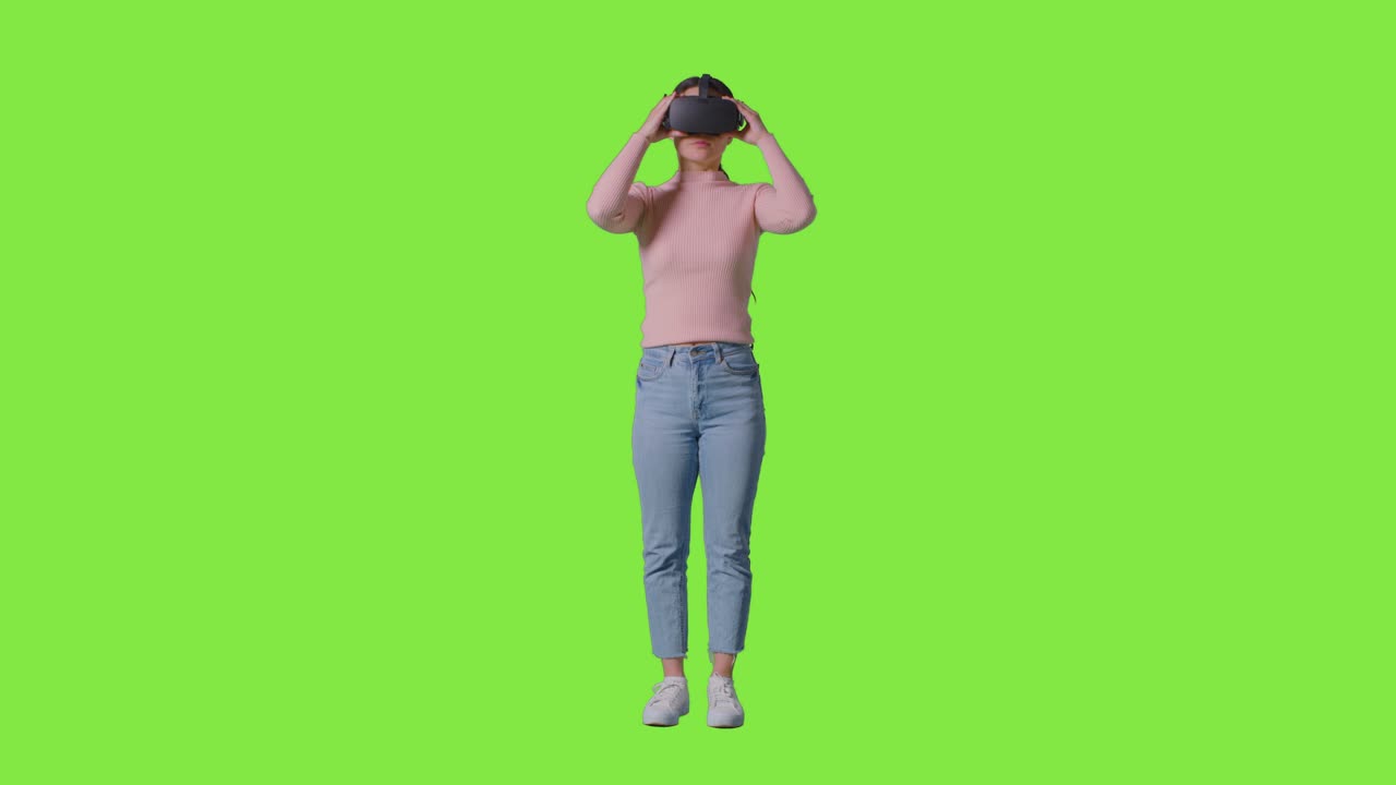 Full Length Shot Of Woman Wearing Virtual Reality Headset And Interacting Against Green Screen Studio Background