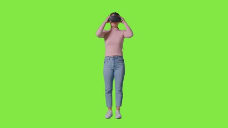 full length shot of woman wearing virtual reality headset and interacting against green screen studio background