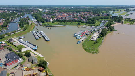 Aerial-of-multiple-river-cargo-boats-docked-at-small-harbor