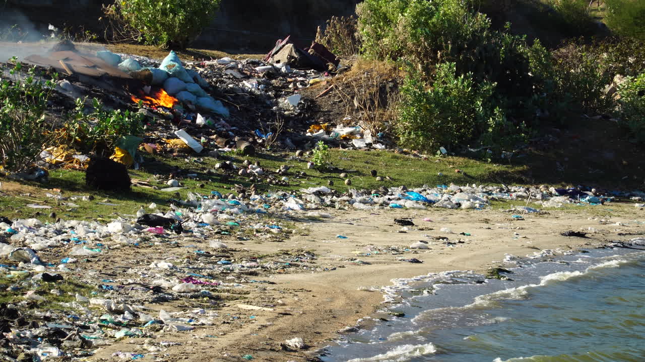 Heap of rubbish being burned on edge of Vietnamese beach
