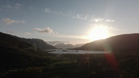 drone shot of glencoe village and loch leven on summer evening, featuring highlands in background and sun flare