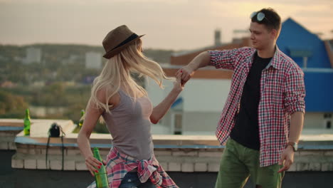 loving couple in red plaid shirts dance on the roof. girl with beer spinning in dance with her russian boyfriend.