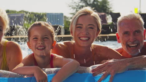 smiling multi-generation family on summer holiday relaxing in swimming pool on airbed