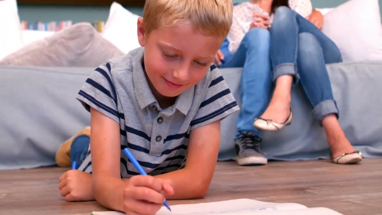 아들 은 부모 가 그를 지켜보는 동안 그림 을 그리고 있다