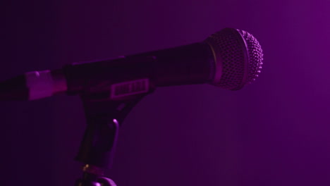 close up shot of single microphone on stage with purple haze lighting and camera tracking in and out