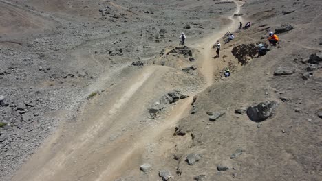 Mountain-biker-going-fast-downhill-a-rocky-mountain-path-and-jumping-over-a-hole-using-a-dirt-ramp