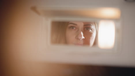 view of a hand with dark nail polish opening a car's front mirror. blurry, close-up shot, handheld camera. perfect for scenes depicting self-reflection, introspection, or routine car activities