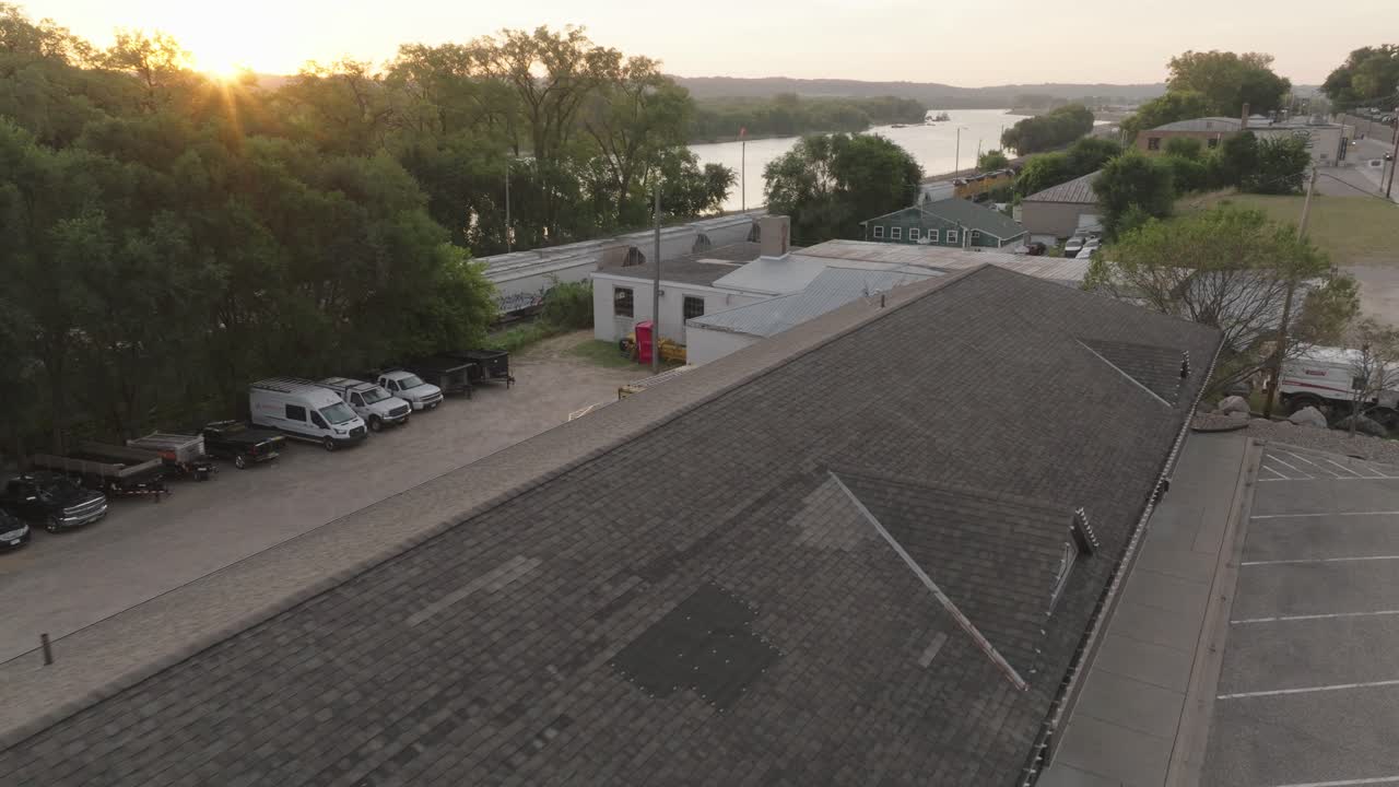 vista aérea de un techo comercial con parches de reparación visibles y un fondo de amanecer.