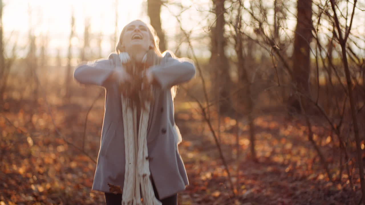 mujer feliz positiva tirando hojas en otoño en el parque 3