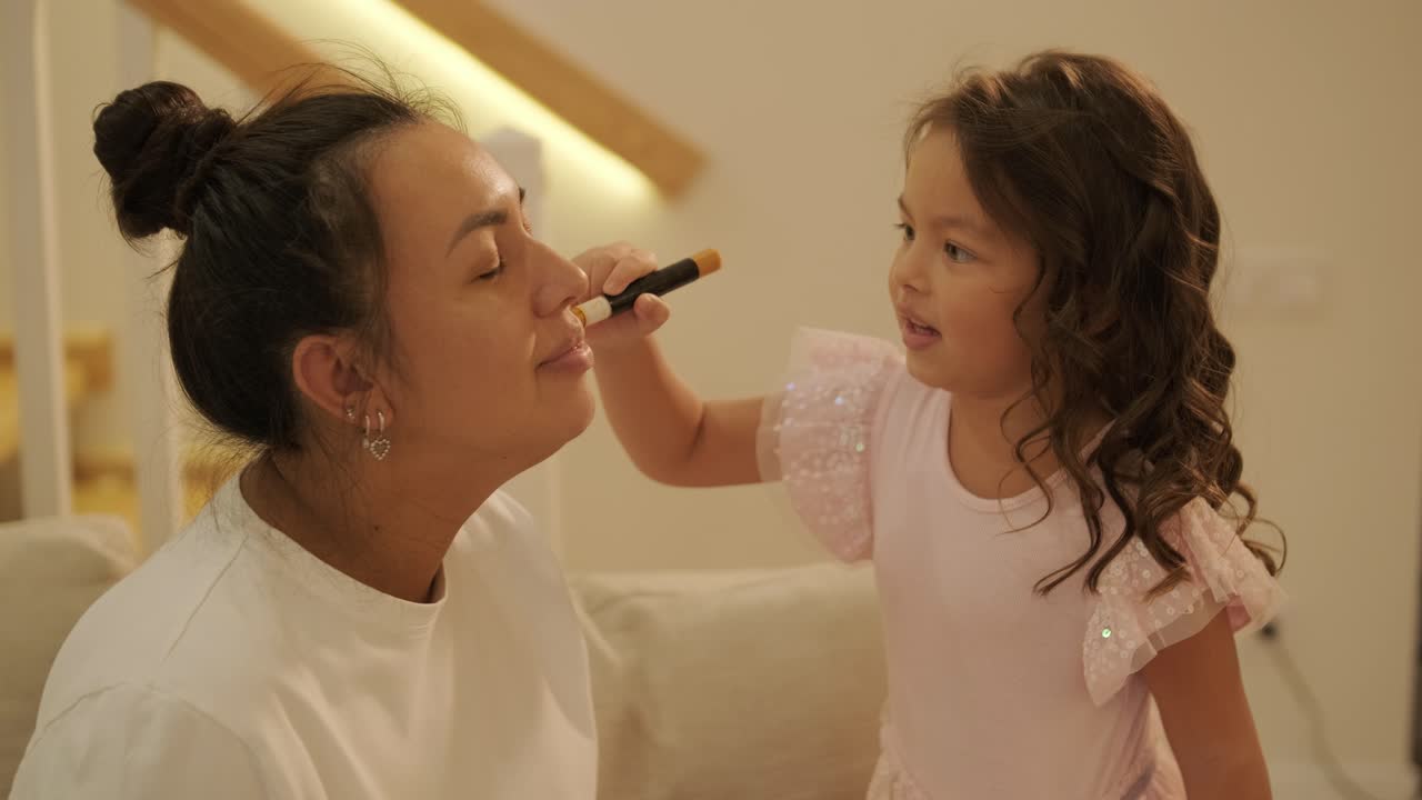 Little Girl Applying Makeup to Her Pregnant Mother at Home