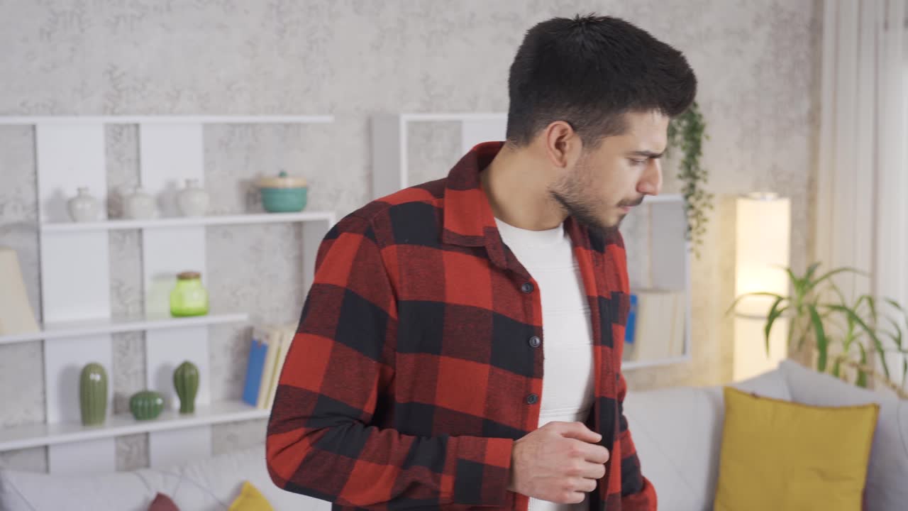 Young man smells bad at home and looks around.