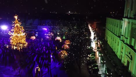 plaza del ayuntamiento de kaunas con árbol de navidad y fila de autos esperando durante la nevada, vista aérea