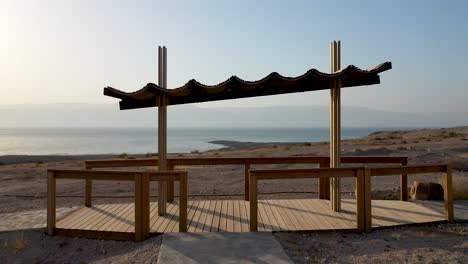 tiro aéreo de mosca bajo un cobertizo de picnic a la vista panorámica del mar muerto, israel, día soleado