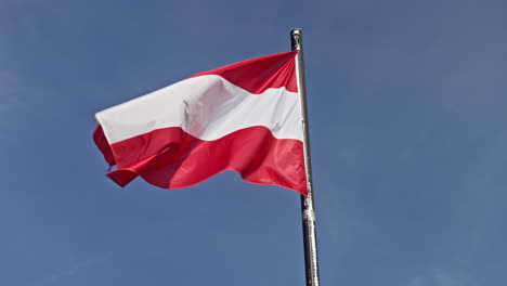 el primer plano en cámara lenta captura la bandera austriaca balanceándose graciosamente en el viento.