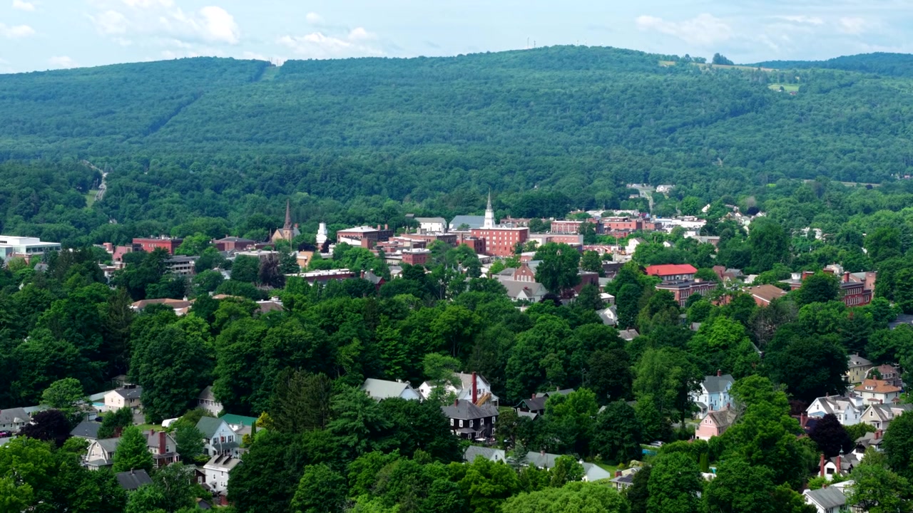 Vista elevada de drone da histórica área central de Greenfield com ruas residenciais arborizadas e campanários de igrejas situados abaixo de colinas verdes ondulantes, Franklin, Massachusetts, EUA