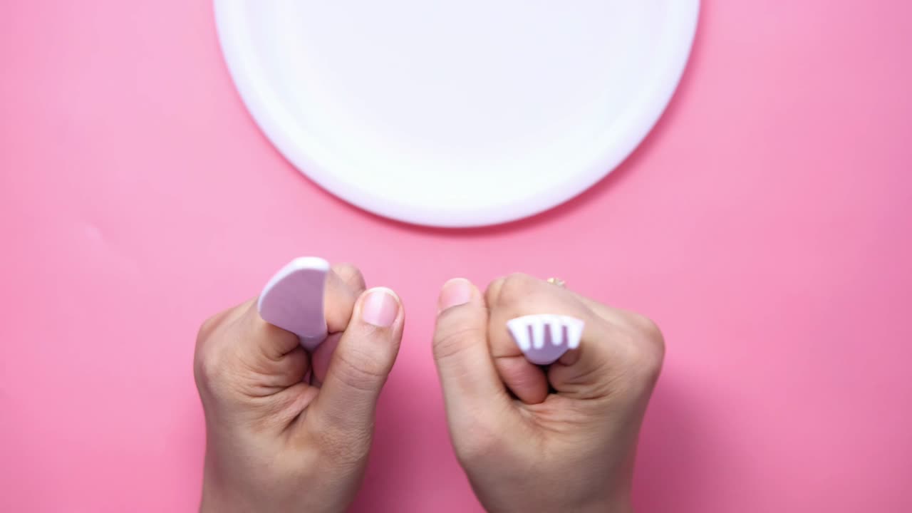 mano sosteniendo cubiertos y plato vacío en madera rosa arriba hacia abajo