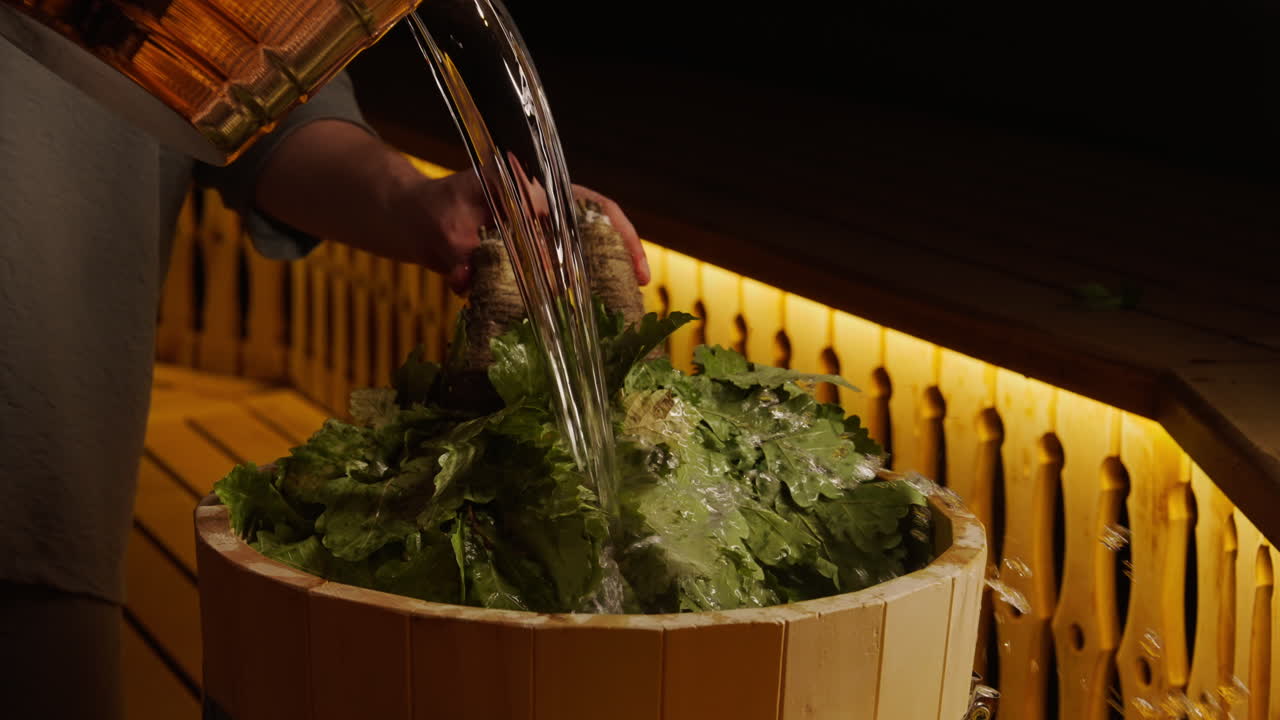 Woman pouring water over herbs in a wooden barrel