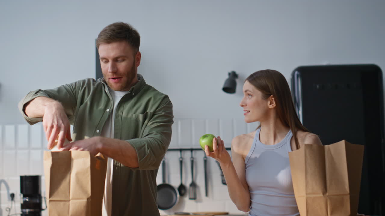 Family couple unpacking groceries in white kitchen closeup. Happy man and woman
