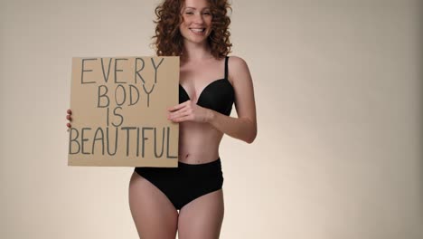 cheerful caucasian red head woman in underwear in the studio holding a banner.