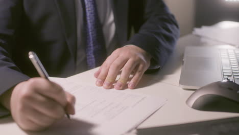 unrecognizable man in suit filling in application form