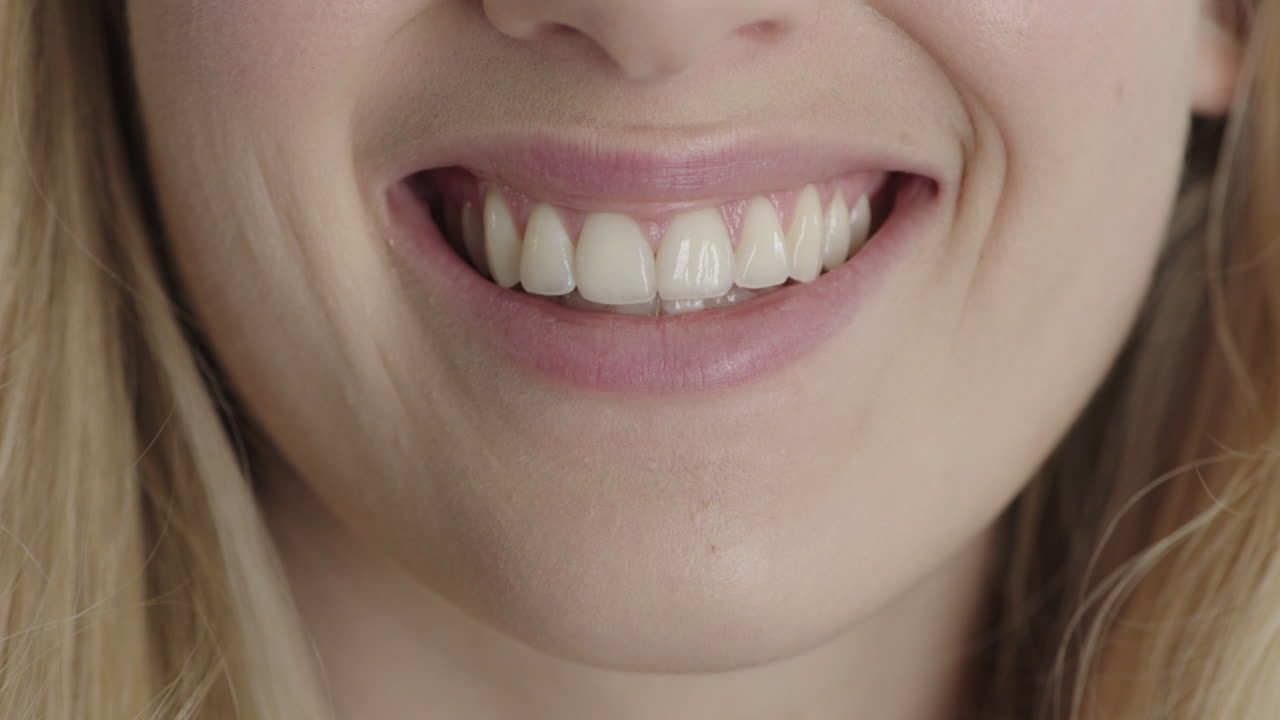 cerrar la boca de una mujer rubia sonriendo feliz mostrando dientes blancos saludables salud dental