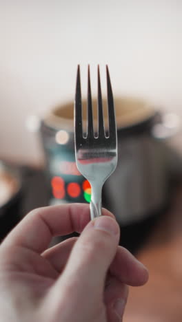video de pov de mano de una persona girando un tenedor con las luces parpadeantes de una cocina múltiple en el fondo borroso