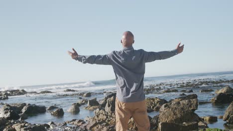 hombre afroamericano de alto nivel extendiendo los brazos en la playa, cámara lenta