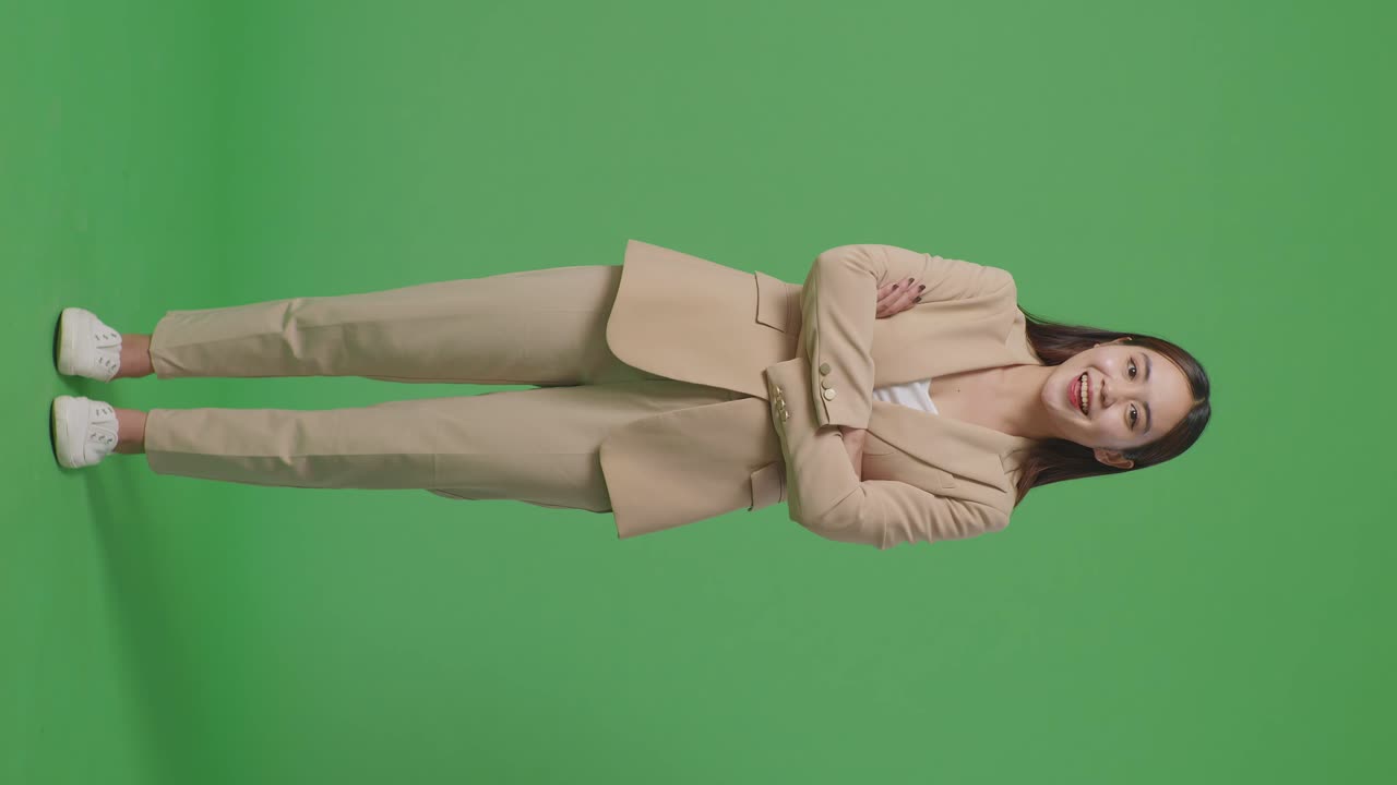 Full Body Of Asian Business Woman Crossed Arms And Warmly Smiling On Green Screen Background In The Studio