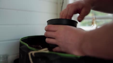 Hands-Of-Gardener-Putting-Soil-On-Pots---Close-Up