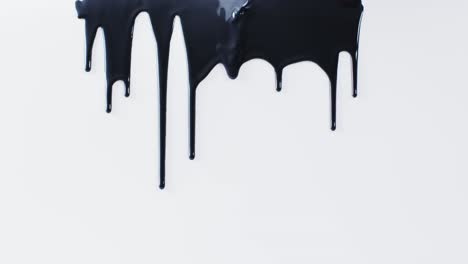 close up of black paint shapes on white background with copy space, slow motion