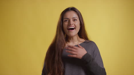 studio portrait of excited woman celebrating good news standing against yellow background 1