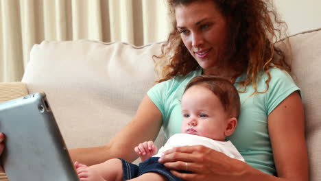 madre usando una tableta con el bebé en el regazo