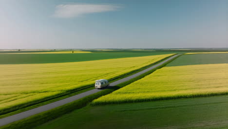 camper van driving through yellow rapeseed fields