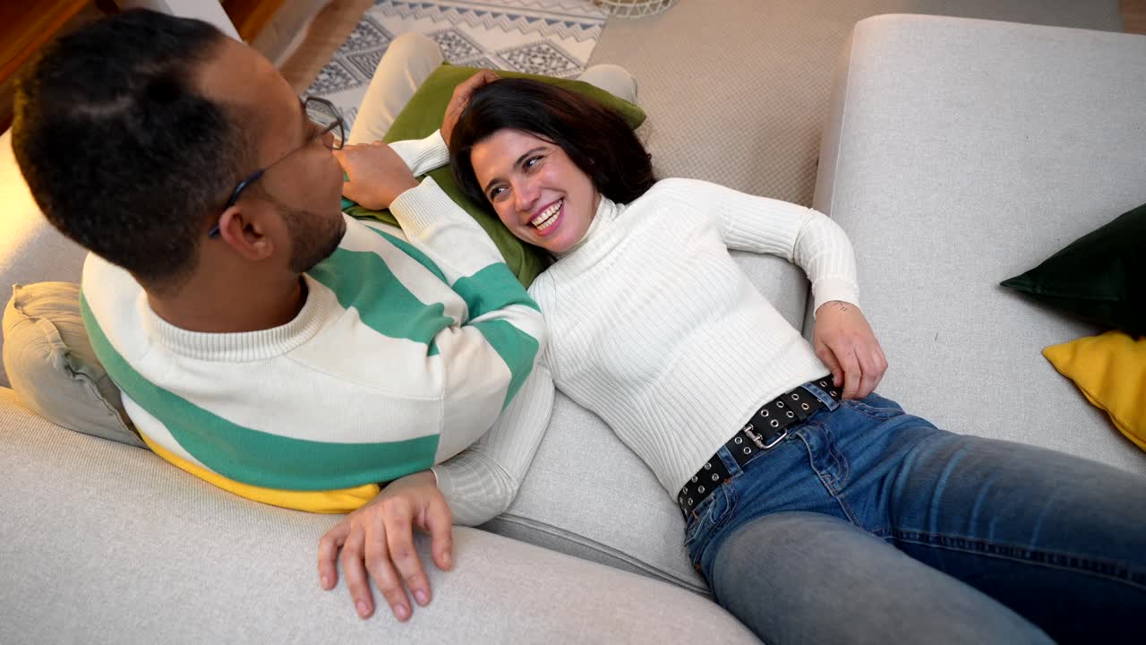 Happy Couple Lying on Sofa and Talking in Living Room