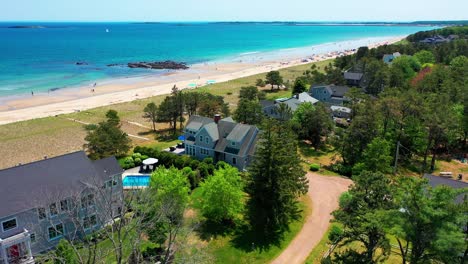 aerial view of a prime beach cottage in maine. oceanfront real estate with sandy yard, patio, deck, and beautiful sea views. perfect family getaway or vacation home on the atlantic coas