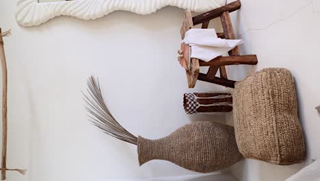 vertical of boho decor in bohemian bedroom - rustic leather journal on a wooden chair and dried palm leaf in handmade woven vase, room furnishing